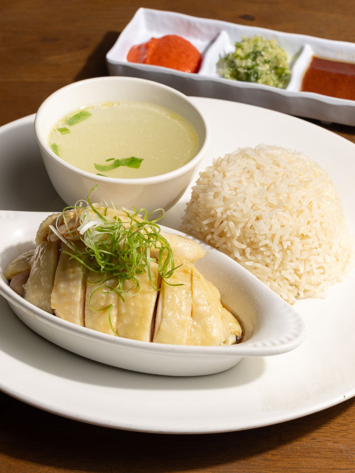 Singapore-style Hainanese chicken rice with broth and chili, ginger-scallion, and dark soy.